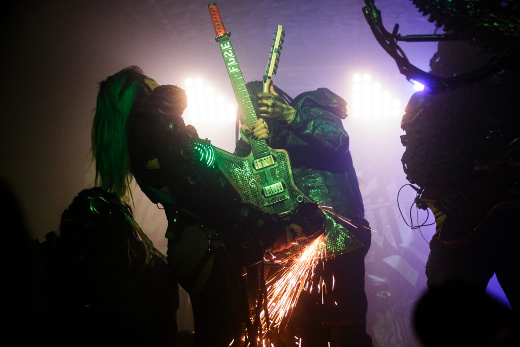 Sick and Beautiful band performing live. Sparkles erupt from the guitar as the singer attacks it with an angle grinder